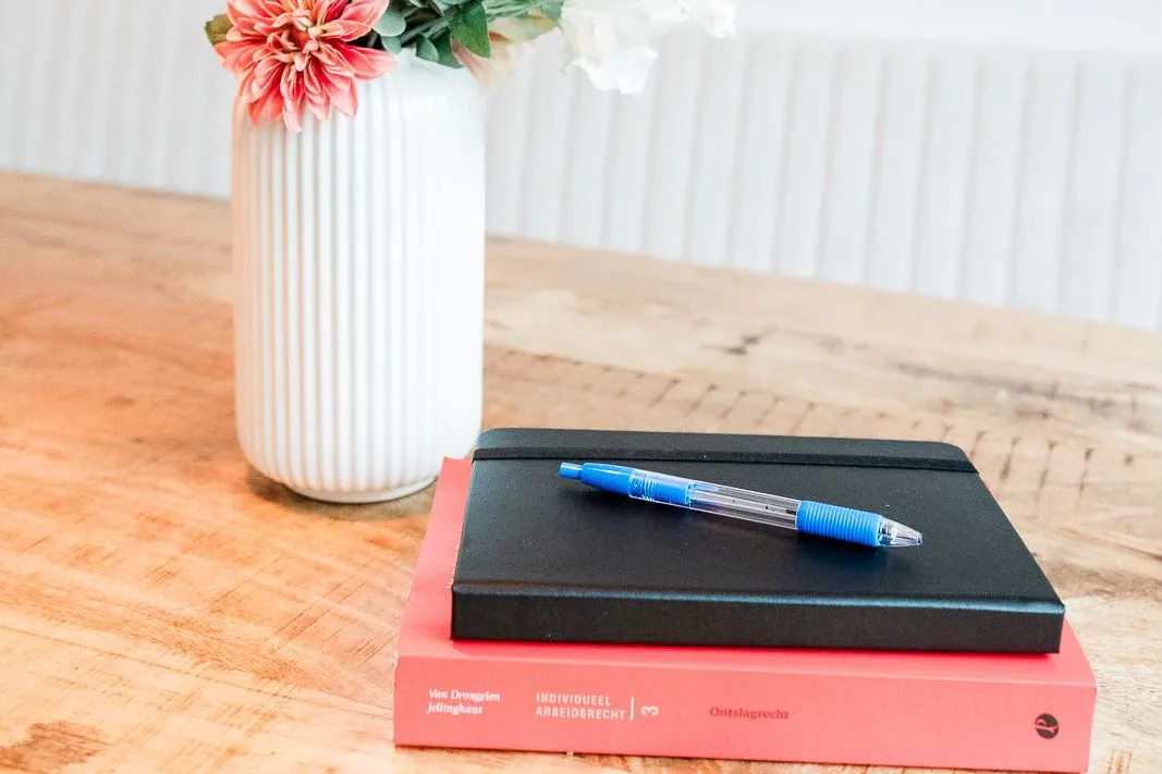 Notitieboek en boek over ontslagrecht op een houten tafel